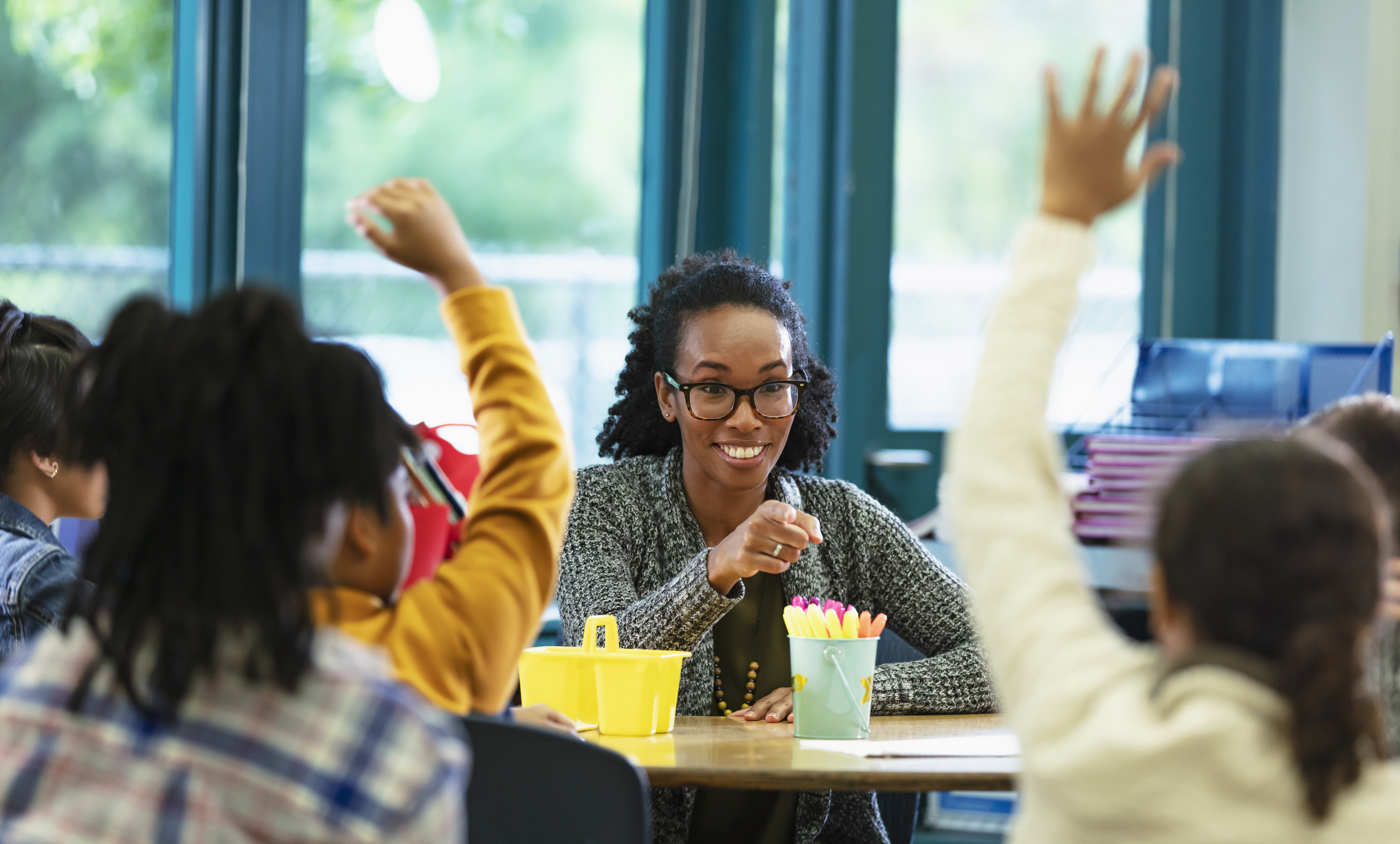 Young female teacher smiling and pointing at one of her students