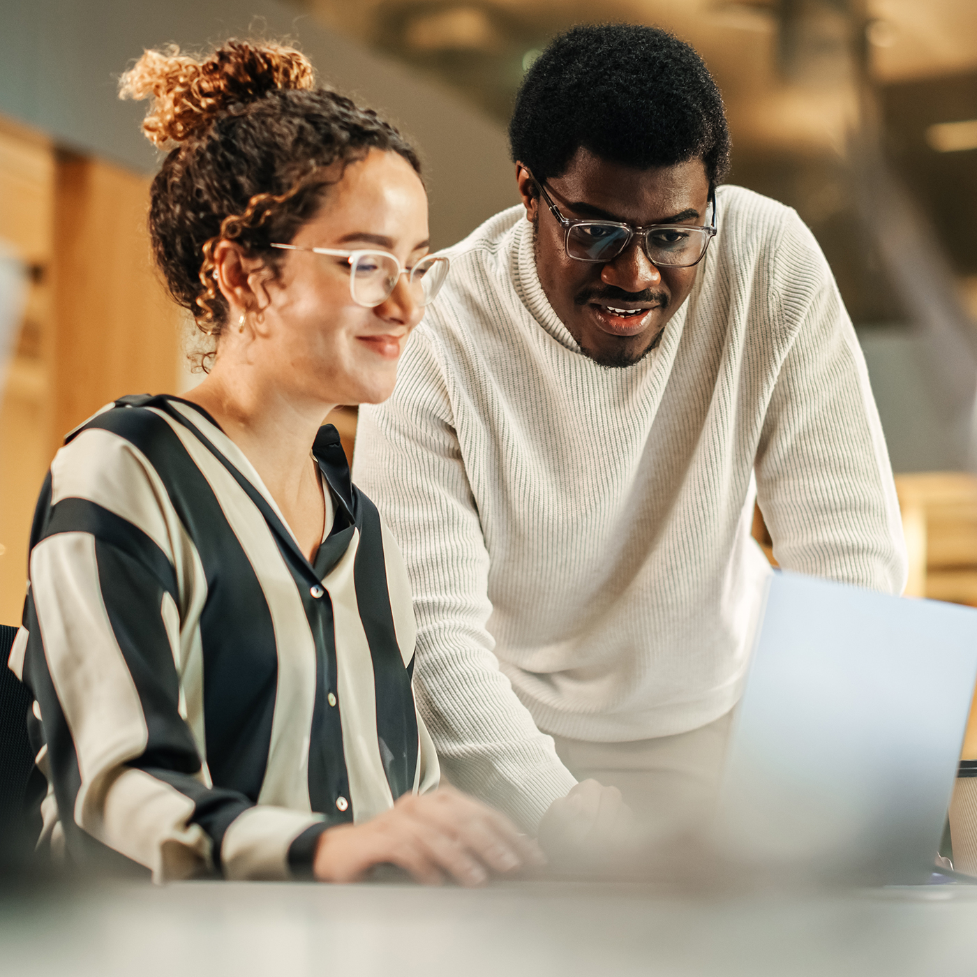 Young male assisting a young woman on a laptop
