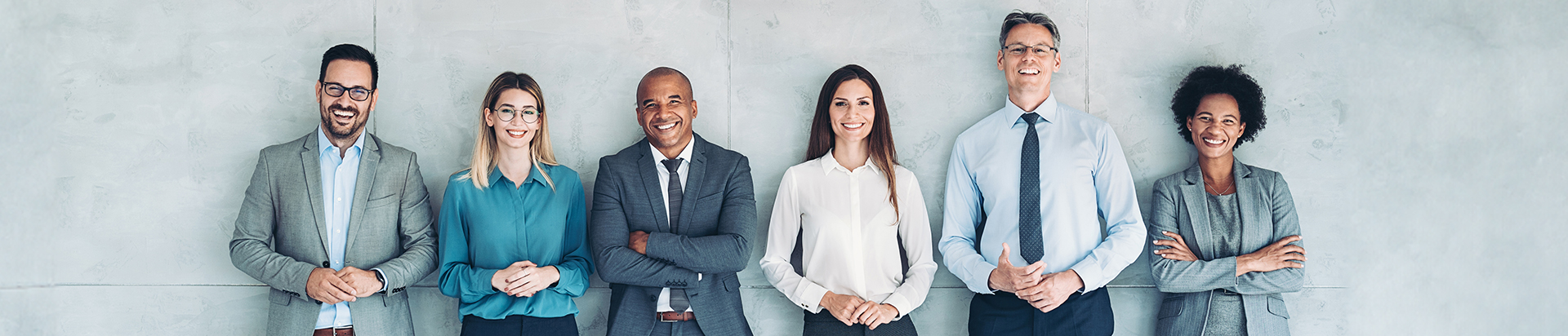 Wide shot of a diverse group of well dressed, professional people smiling toward the camera