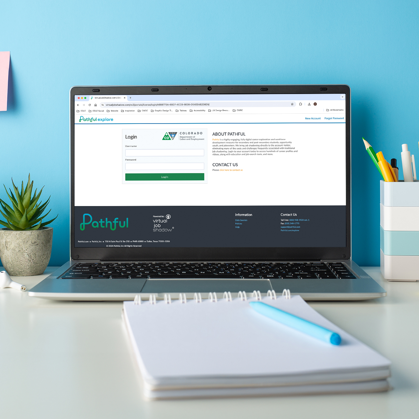 Laptop on a wood desk against a vibrant background, with a screen displaying the homepage for Pathful Explore