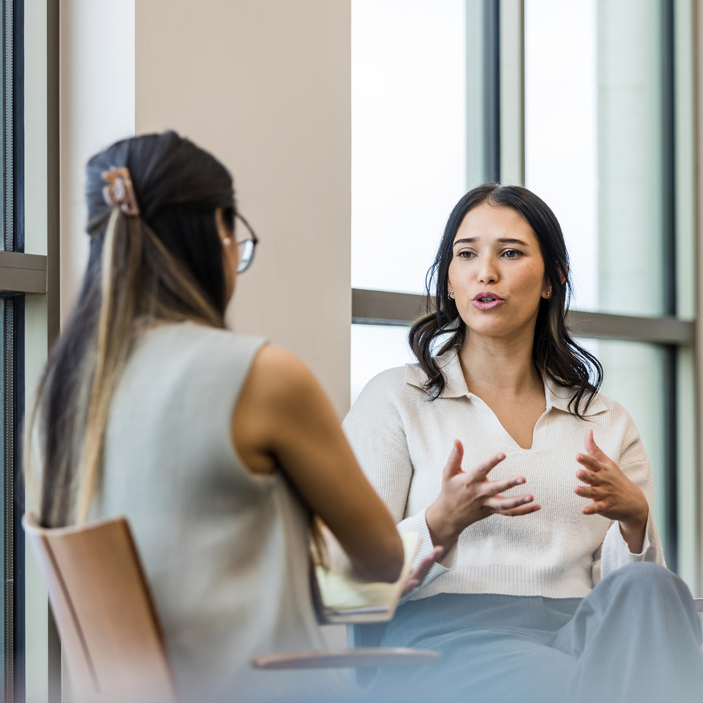 Two young women seated at a small table talking to one another