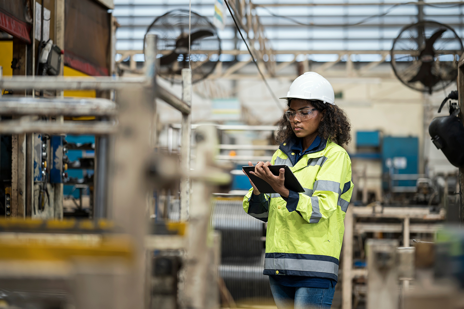 Image of a manufacturing worker writing notes in tablet.
