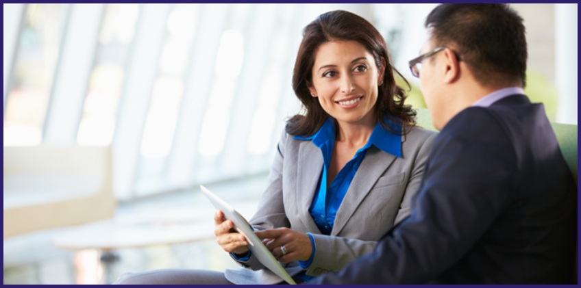 Two people reviewing a tablet in a modern office setting.