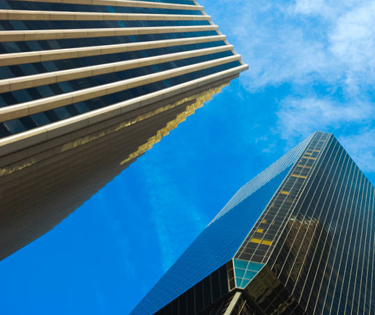 Angled worm's-eye view of two buildings against a blue sky.