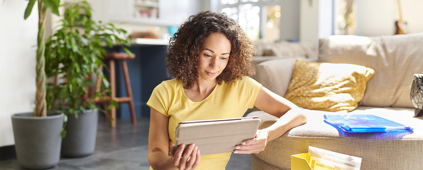 A woman sitting in a living room looking at her tablet